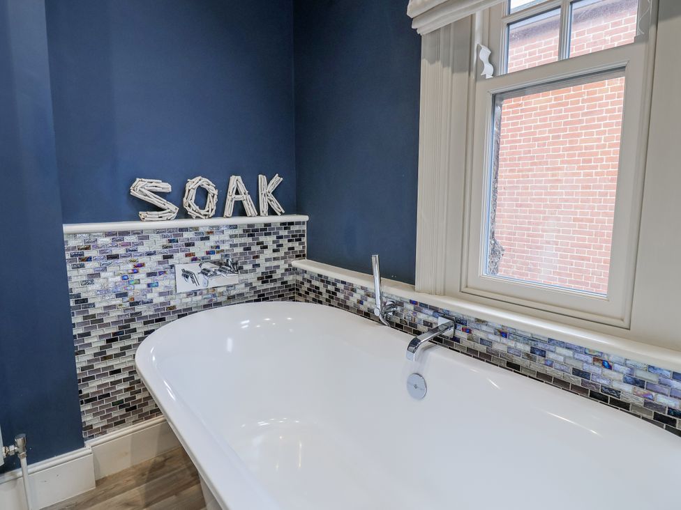 A bathtub with a mosaic tile surround at Holly Lodge in Aldeburgh
