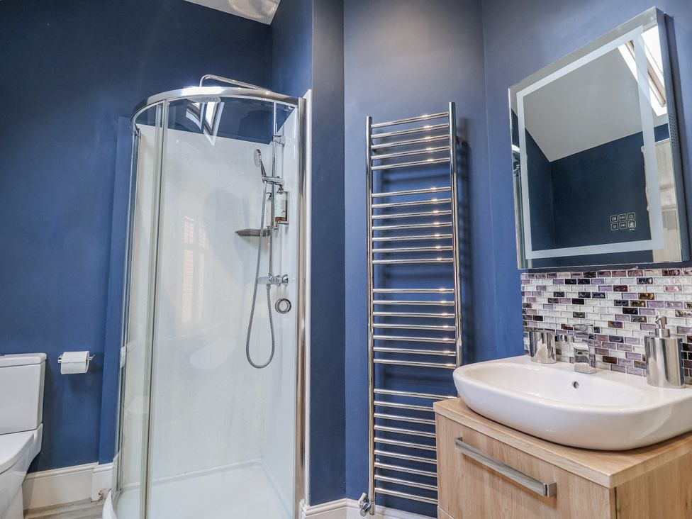 A bathroom with a shower, toilet, sink, and towel rack at Holly Lodge in Aldeburgh