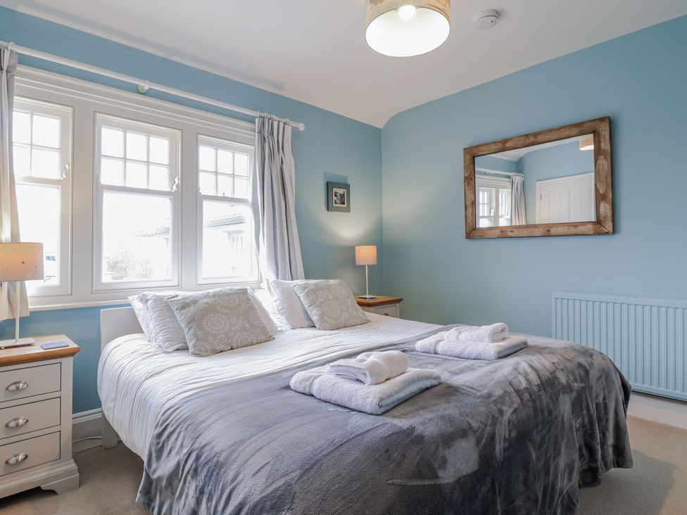 A bedroom with a bed and windows at Holly Lodge in Aldeburgh