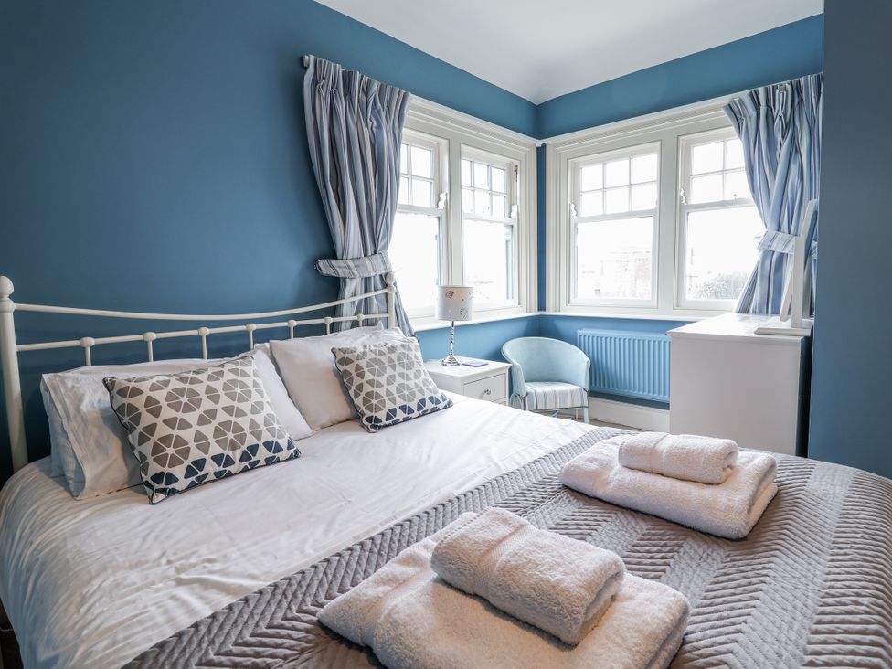A bedroom with a bed and windows at Holly Lodge in Aldeburgh