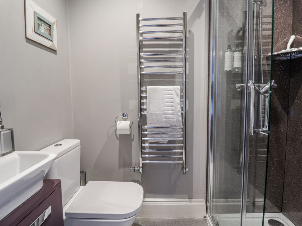 A bathroom with a toilet, sink, towel rack and shower at Holly Lodge in Aldeburgh