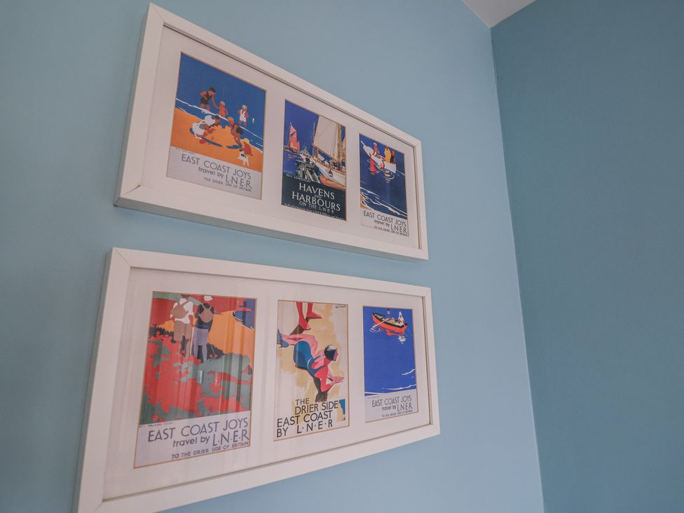 A display of framed posters on a blue wall at Holly Lodge in Aldeburgh