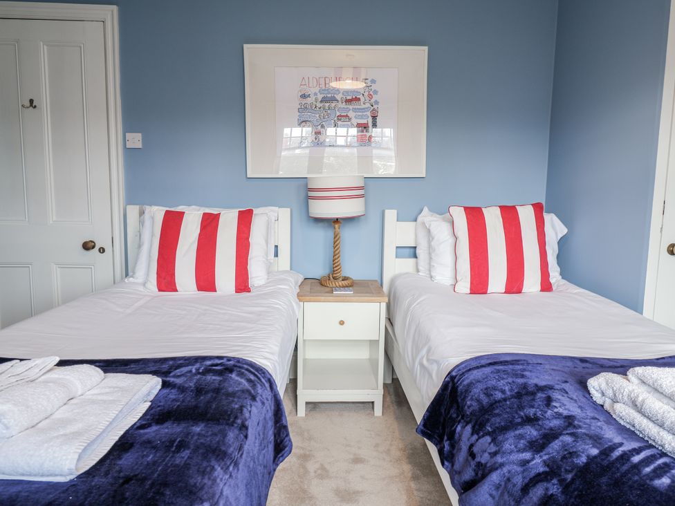 A bedroom with two beds and a lamp on a bedside table at Holly Lodge in Aldeburgh