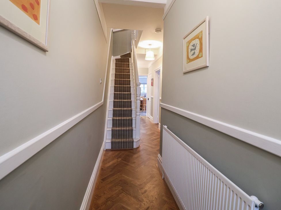 A hallway with a staircase and framed artwork at Lavender House, Aldeburgh