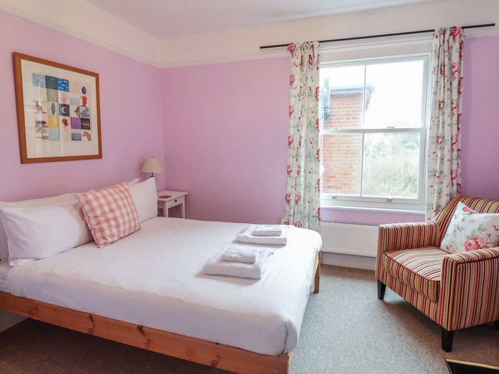 A bedroom with a bed and chair at Lavender House, Aldeburgh
