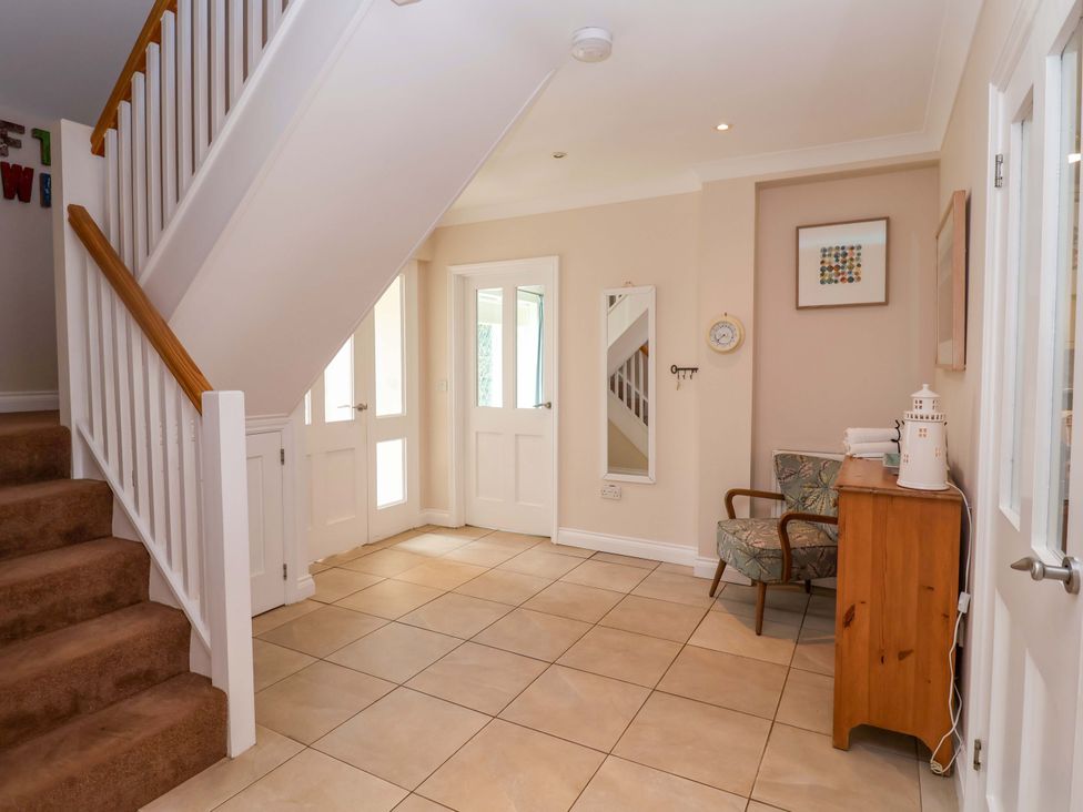 A hallway with a staircase and a chair at Seadrift Dunwich Near Westleton