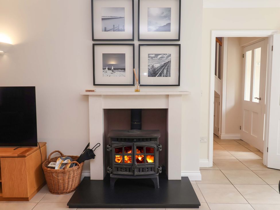 A living room with a fireplace and pictures on the wall at Seadrift Dunwich Near Westleton