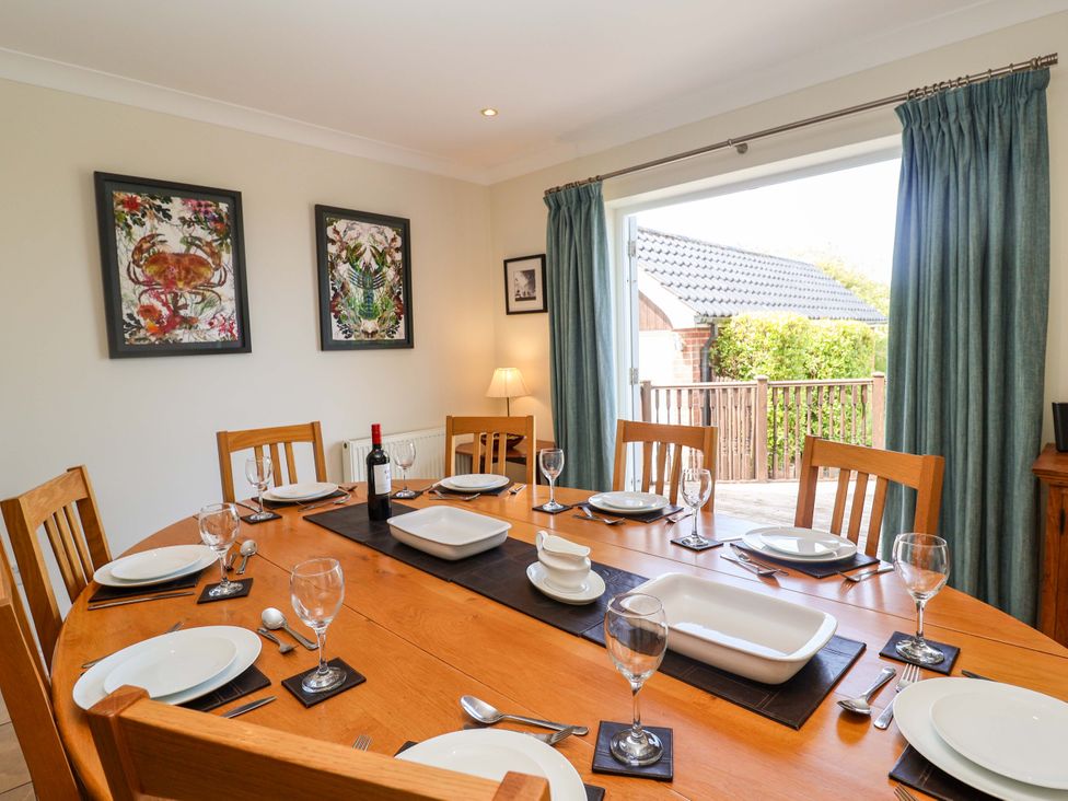 A dining room with a table set for a meal at Seadrift in Dunwich Near Westleton
