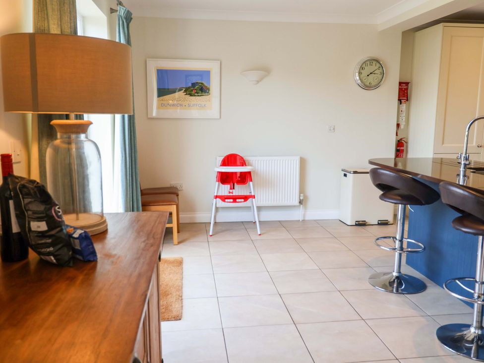 A kitchen with a high chair and bar stools at Seadrift Dunwich Near Westleton
