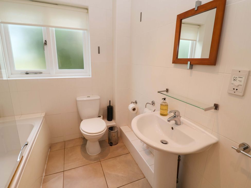 A bathroom with a bathtub, sink, toilet, and window at Seadrift in Dunwich Near Westleton