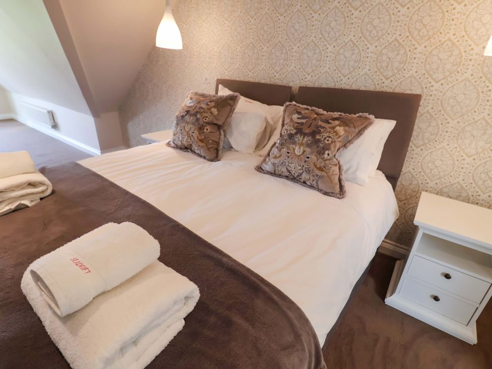 A bedroom with a bed and bedside table at Seadrift in Dunwich Near Westleton