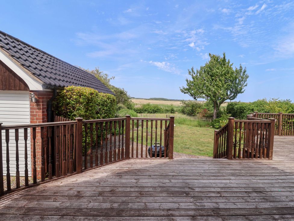 An outdoor area featuring a wooden deck and a tree at Seadrift Dunwich Near Westleton