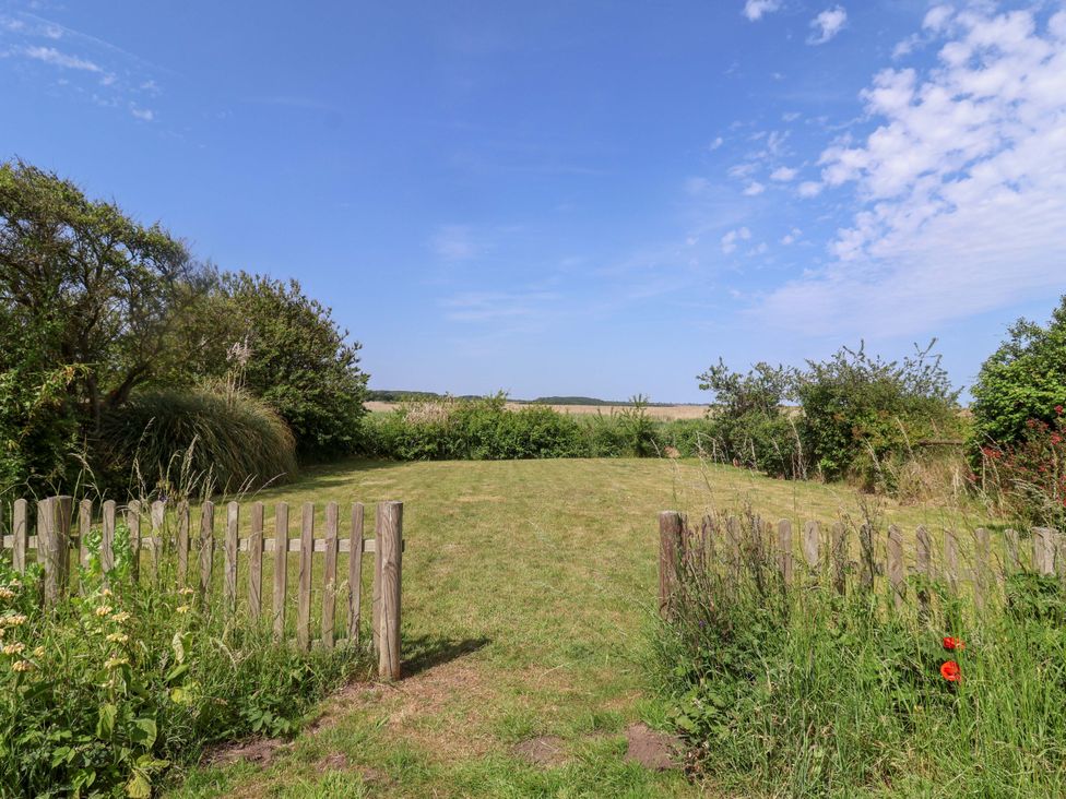 A garden with a fence and grassy area at Seadrift Dunwich Near Westleton