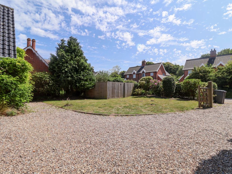 A garden with a gravel driveway and trees at Seadrift in Dunwich Near Westleton