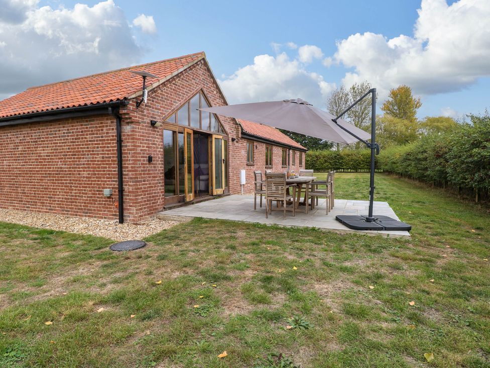 A garden with outdoor seating and a parasol at The Mulberry, nr Bungay