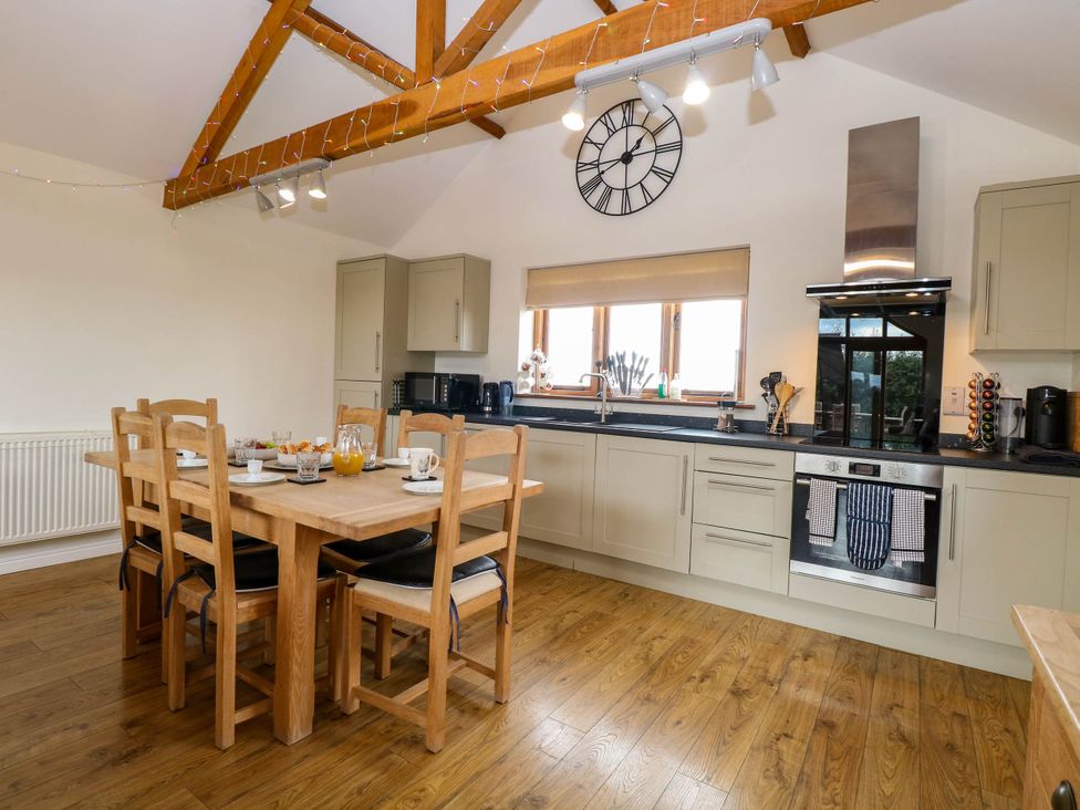A kitchen with a dining table and wooden chairs at The Mulberry, nr Bungay