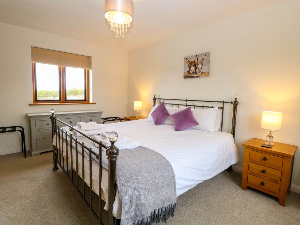A bedroom with a bed, nightstand, and window at The Mulberry, nr Bungay