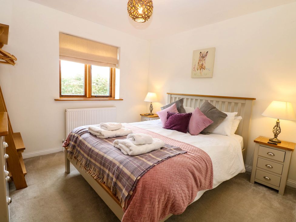 A bedroom with a bed and nightstand at The Mulberry, nr Bungay