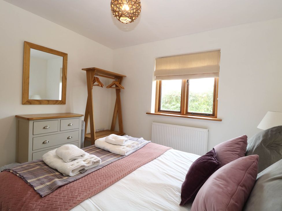 A bedroom with a bed, dresser, and mirror at The Mulberry, nr Bungay Bungay