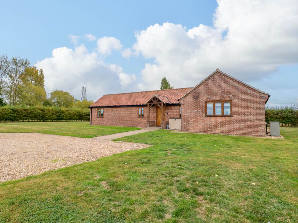A brick house with a gravel pathway and garden area at The Mulberry, nr Bungay