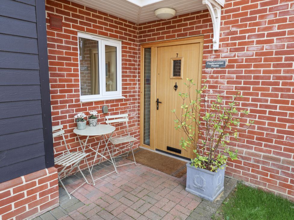 An entrance with a wooden door and a small table and chairs at Meadowsweet House Blythburgh near Reydon