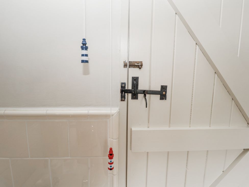 A door with a bolt and decorations in a bathroom at Mariners Cottage, King Street, Aldeburgh
