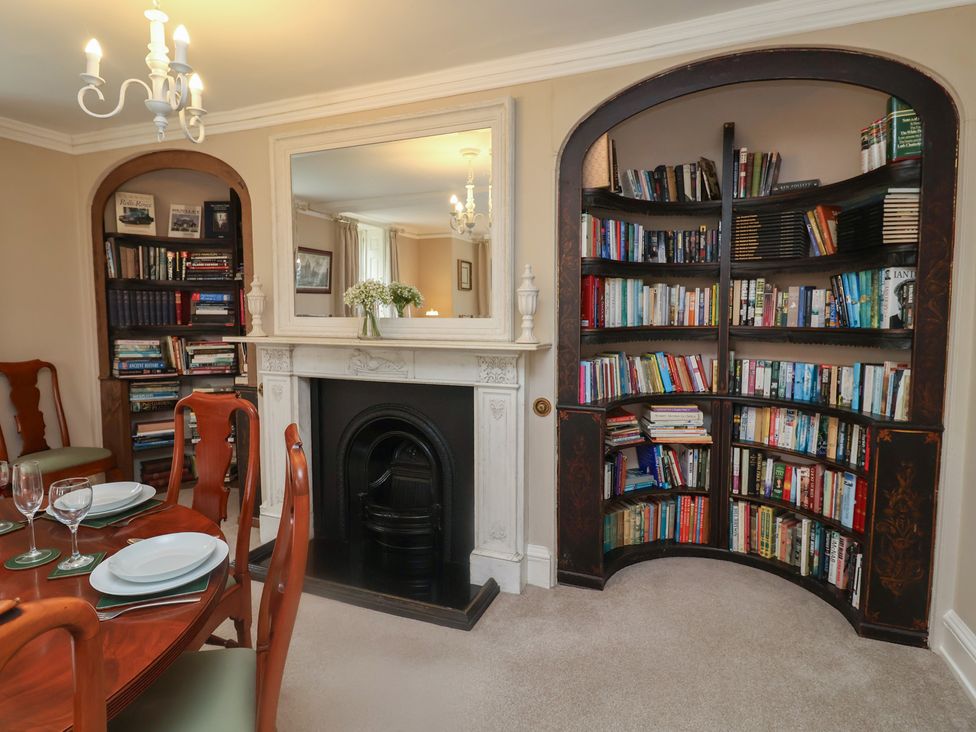 A dining room with a table and bookshelf at Henstead Hall Henstead near Beccles
