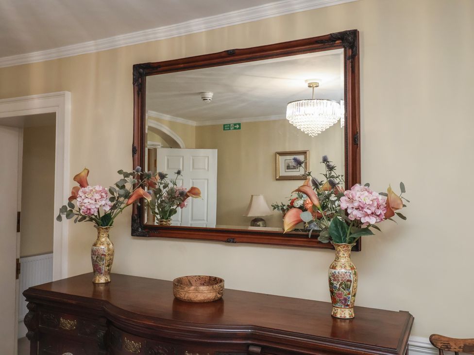 A wooden table with vases of flowers and a mirror at Henstead Hall Henstead near Beccles
