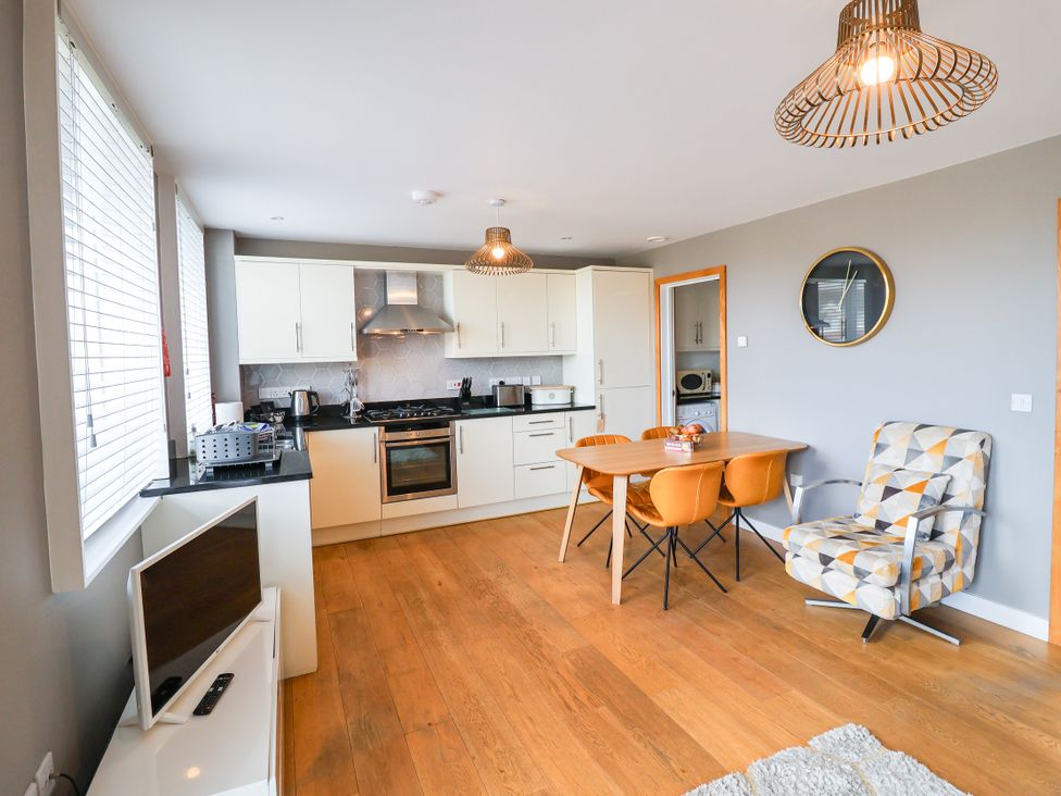 A kitchen with cabinets and a dining table at The Hive, Southwold