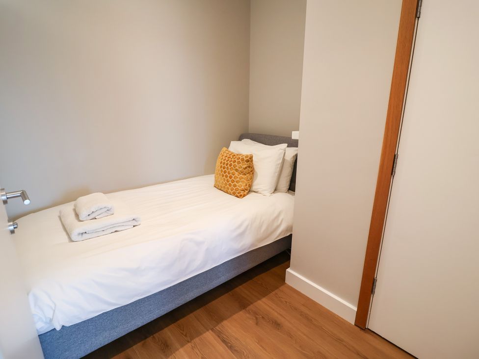 A bedroom with a single bed and towels at The Hive, Southwold