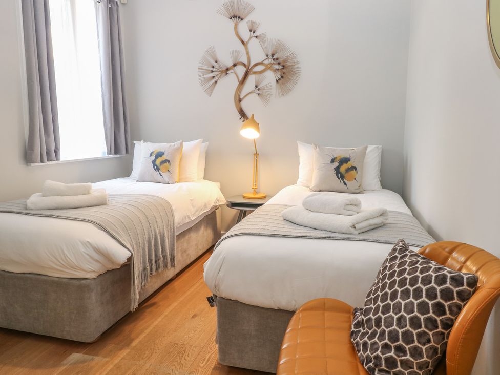 A bedroom with two beds and a chair at The Hive, Southwold