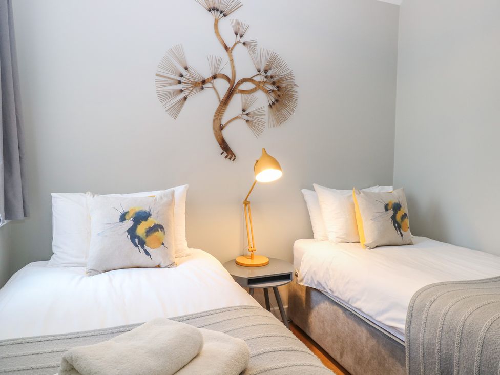 A bedroom with twin beds and wall art at The Hive, Southwold