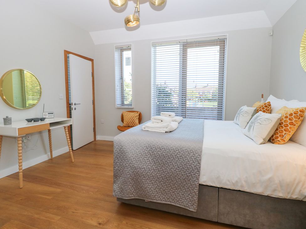 A bedroom with a bed and a chair at The Hive, Southwold