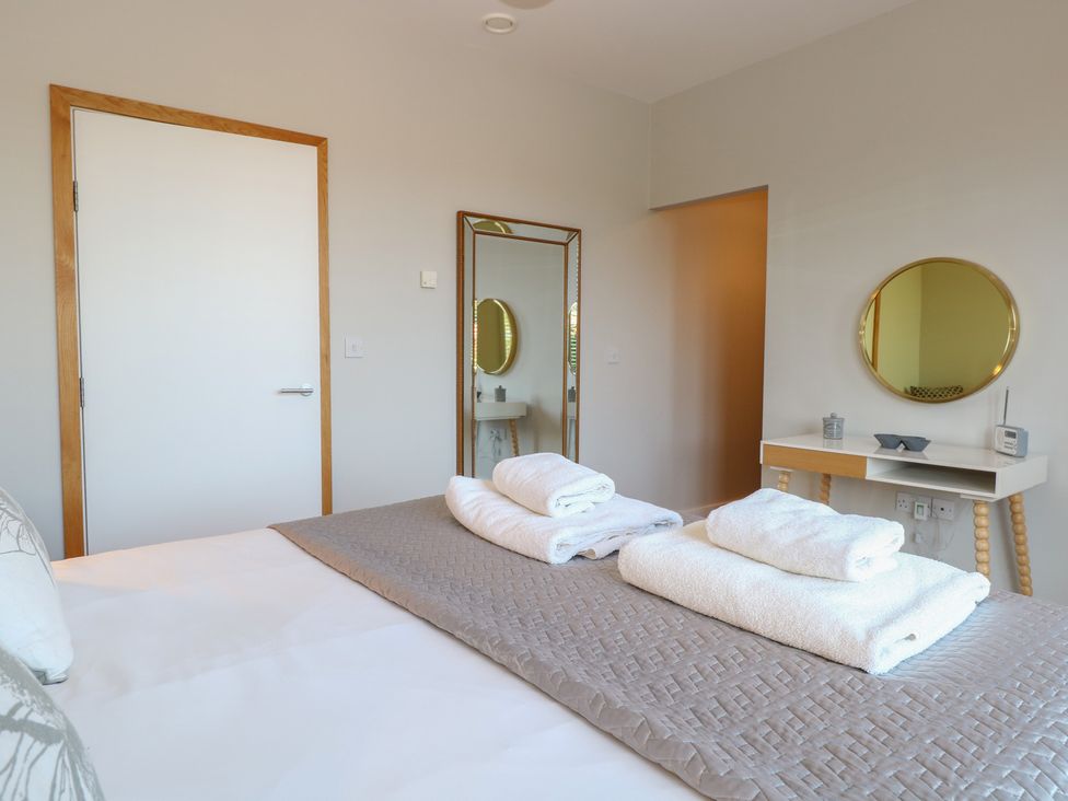 A bedroom with a bed and towels arranged at The Hive, Southwold