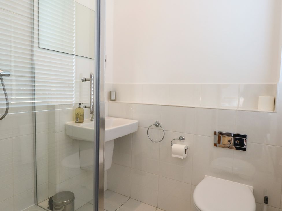 A bathroom with a shower, sink, and toilet at The Hive, Southwold