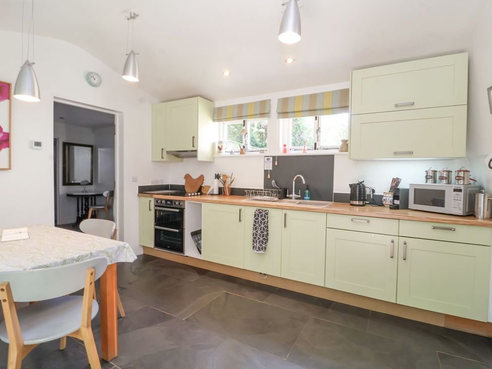 A kitchen with cabinets, oven, and dining table at Yew Tree Farm Barn and Stable Framlingham