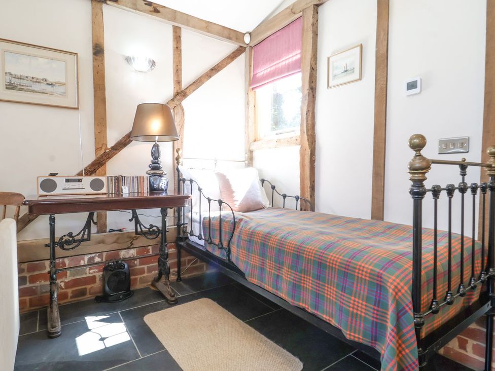 A bedroom with a bed, table, and lamp at Yew Tree Farm Barn and Stable in Framlingham