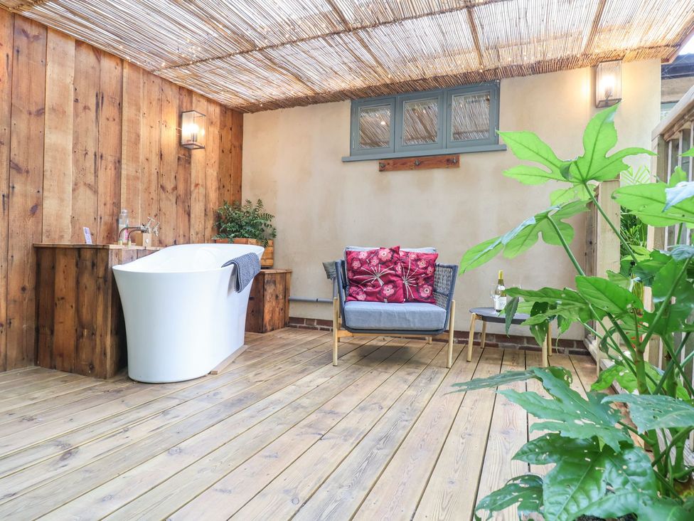 A bathroom with a bathtub, chair, and greenery at Yew Tree Farm Barn and Stable in Framlingham