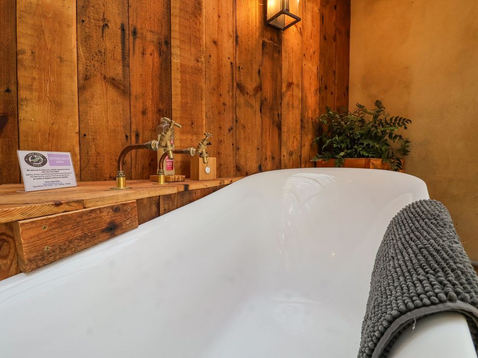 A bathtub with wooden wall and plant at Yew Tree Farm Barn and Stable Framlingham
