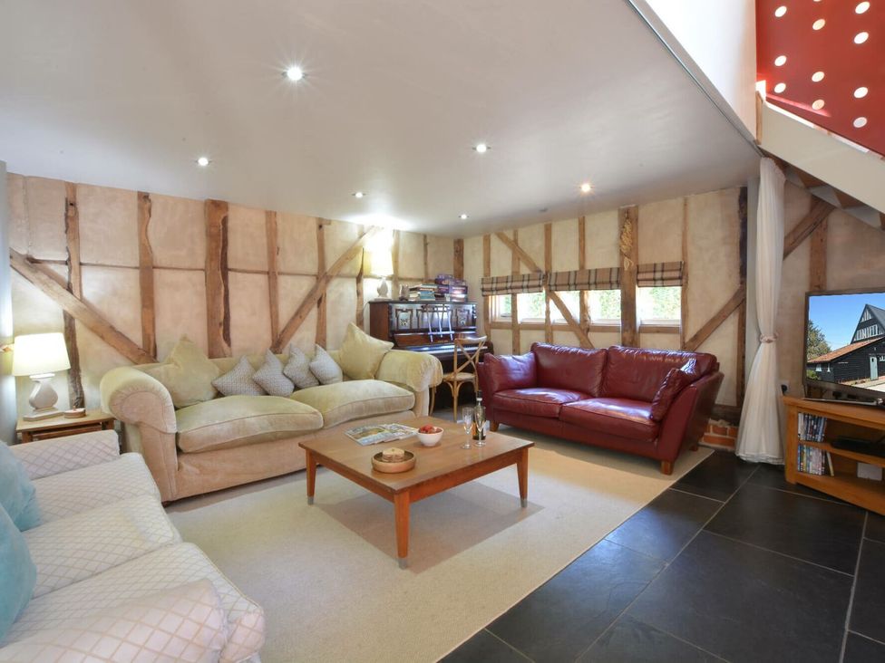 A living room with a red sofa and a coffee table at Yew Tree Farm Barn and Stable Framlingham