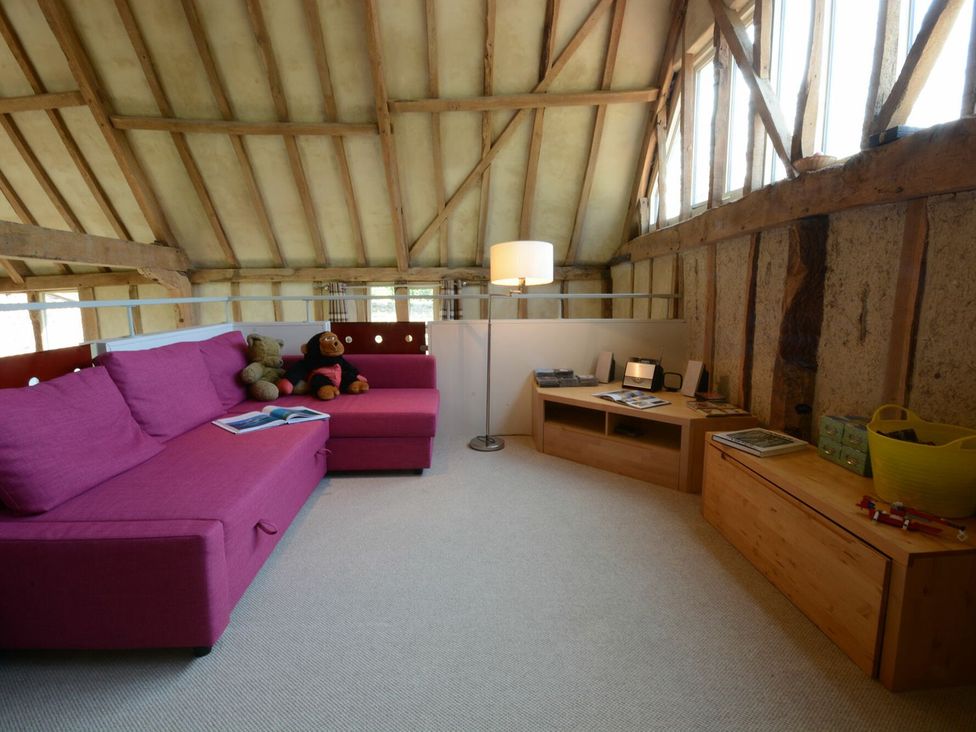 A living room with a pink sofa and wooden furniture at Yew Tree Farm Barn and Stable Framlingham