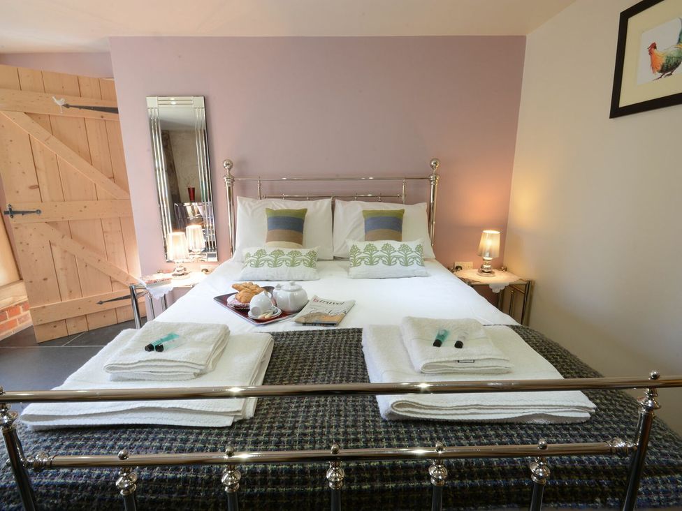 A bedroom with a bed and bedside table at Yew Tree Farm Barn and Stable in Framlingham