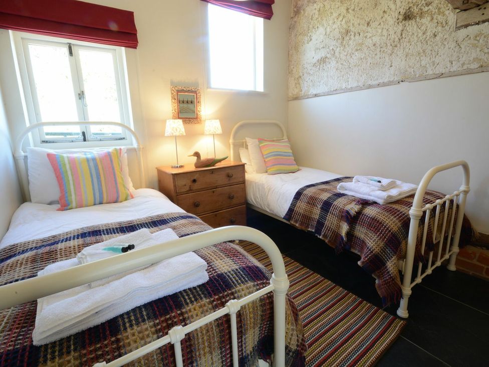 A bedroom with two single beds and a nightstand at Yew Tree Farm Barn and Stable Framlingham