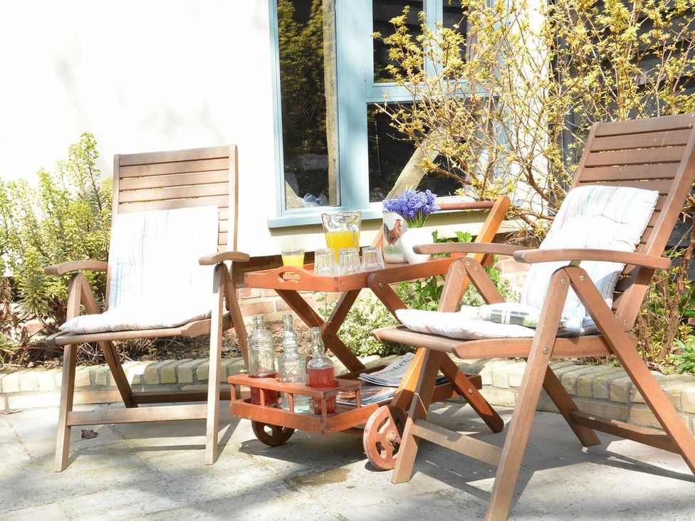 A garden with wooden chairs and a table at Yew Tree Farm Barn and Stable, Framlingham