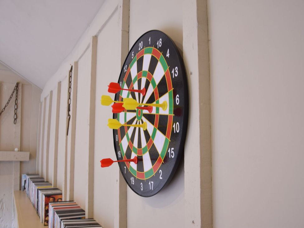 A dartboard with darts on the wall at Yew Tree Farm Barn and Stable in Framlingham