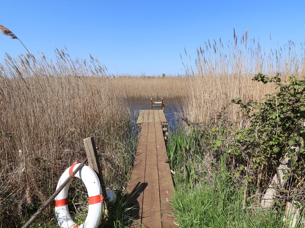 A dock with a lifebuoy and reeds at The Cart House in Sudbourne Near Orford