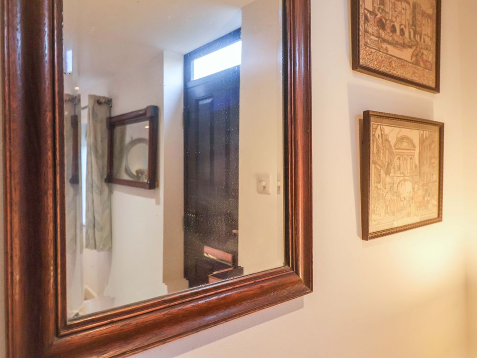 A hallway with a mirror and framed pictures at Pine Cottage in Woodbridge