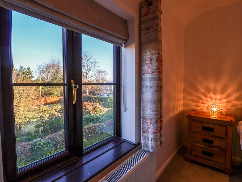 A bedroom with a window and nightstand at Pine Cottage in Woodbridge
