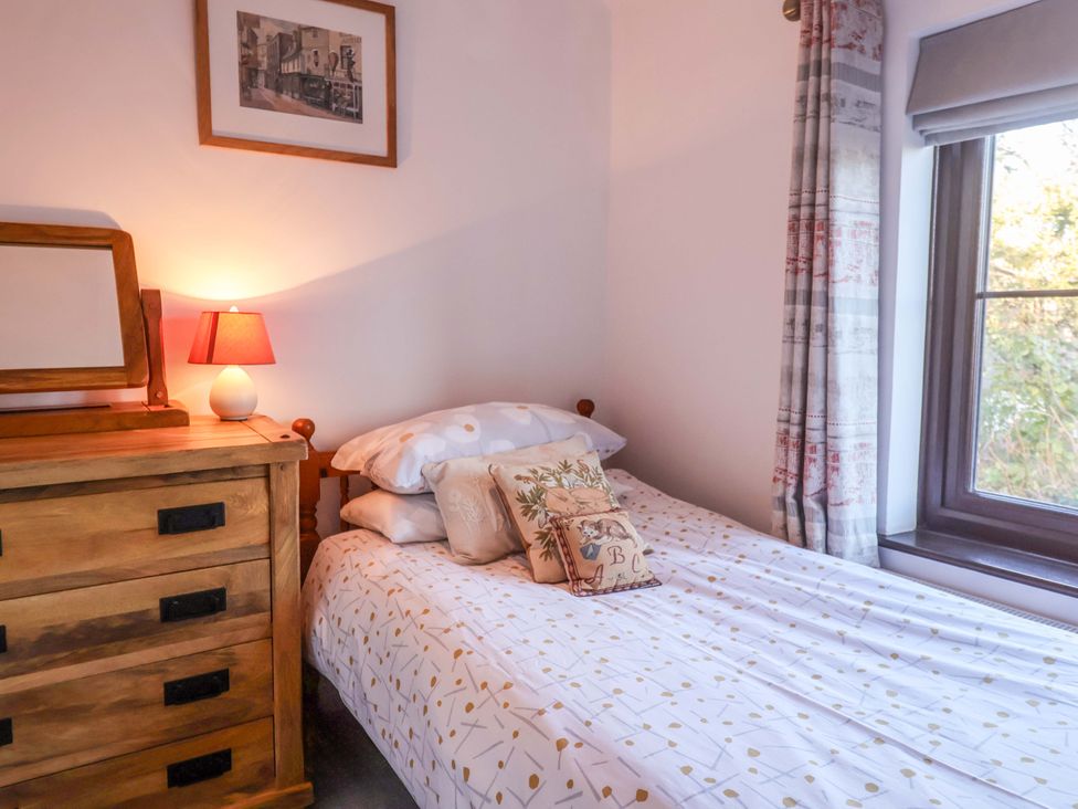 A bedroom with a bed and wooden dresser at Pine Cottage in Woodbridge