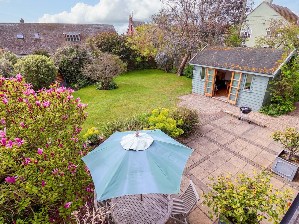 A garden with a green shed and patio furniture at Robert Sadler's Studio in Aldeburgh
